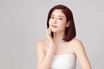 A beautiful young Asian woman with clean, fresh skin against a grey background. Skincare, facial treatment, cosmetology, beauty, and spa. An elegant portrait of an Asian woman.