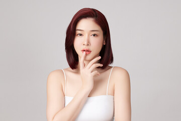 Fototapeta premium A beautiful young Asian woman with clean, fresh skin against a grey background. Skincare, facial treatment, cosmetology, beauty, and spa. An elegant portrait of an Asian woman.