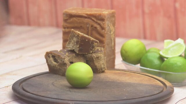Hand Rolling Fresh Green Lime on Wooden Board with Piloncillo Sugar