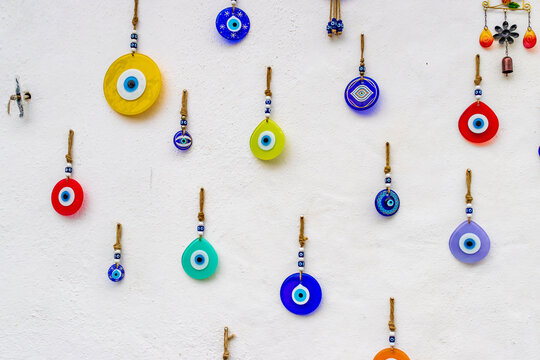 Colorful Turkish evil eye amulets hanging on white wall. Traditional nazar boncuk charms as cultural symbol and souvenir from Turkey.