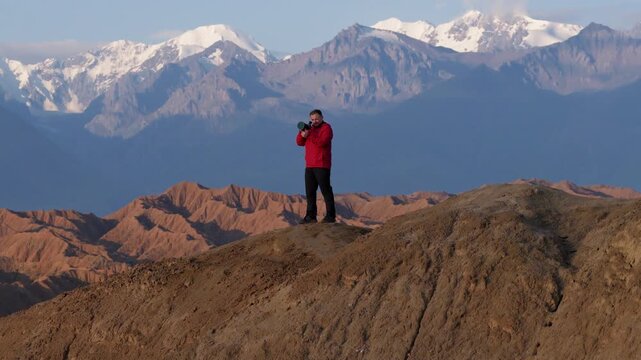 Man With A Camera Standing Over Mountain Overlooking Ak Sai Canyon In Kyrgyzstan. Aerial Drone Shot