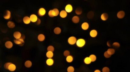 Fototapeta premium Warm yellow, orange, and red bokeh lights shimmering in motion against a black night backdrop, evoking a romantic light tone.