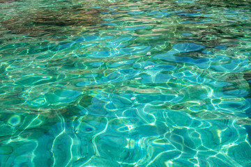Turquoise sea water surface background, shimmering ripples and sunlight reflections, above view