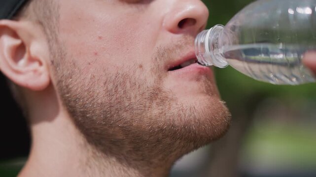 Youthful Water Play, Casual Man Enjoys Splashing Water Outdoors, Man In Backward Cap Engages In Playful Water Spitting Activity, Man With Backwards Cap Shares Fun Summer Water Splashing Moment