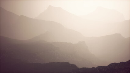 In the early morning, silvery mist envelops towering mountain ranges, creating a serene and ethereal atmosphere. Layers of peaks fade into the distance, enhancing the tranquility of nature.