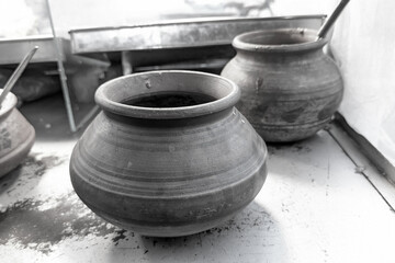 A rustic, round terracotta pot, brown earthenware, shows horizontal lines from its creation. Its a simple, traditional cooking or storage vessel.