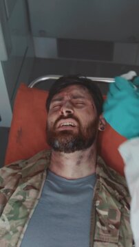 Medical inspection on injured soldier, Injured soldier receives rapid assessment from medic under field conditions
