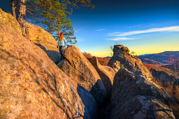 Female hiker walking on rocky mountain ridge at sunset, outdoor hikin