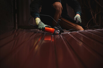 Man hand cutting corrugated metal sheet with an angle grinder,  sparks flying, industrial construction work scene, metal fabrication process, power tool in action, safety concept, workshop or building