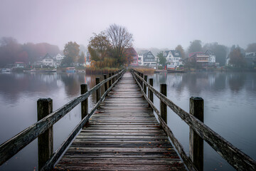 Obraz premium Early morning calm on a wooden pier with mist rising over a tranquil lake
