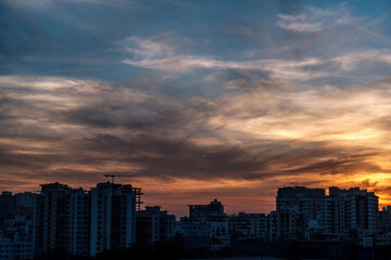 Fototapeta premium Evening scene with lit up and silhouetted buildings against a colourful evening sky at Pune India.