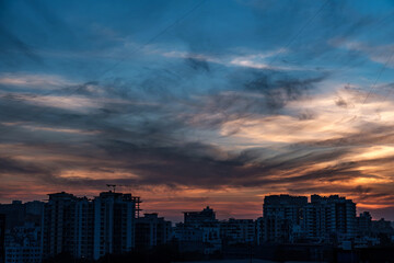 Fototapeta premium Evening scene with lit up and silhouetted buildings against a colourful evening sky at Pune India.