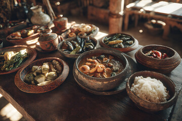 Table filled with various cooked dishes in a rustic setting during a daytime meal
