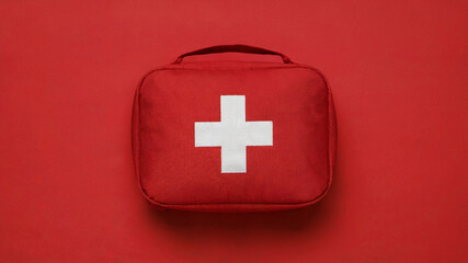 Obraz premium Red First Aid Kit with White Cross on Emergency Background