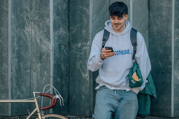 young man on street wall with mobile phone and vintage bicycle with copy-space