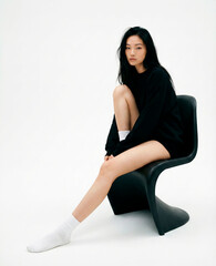 Young woman posing on a minimal black chair