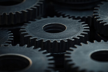 Close-up macro shot of interlocking metal gears, symbolizing teamwork and industry. Detailed view of dark metallic gears meshing together, representing mechanical engineering and industrial processes