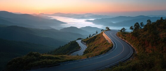 Winding road through mountainous landscape at sunrise with clouds in valley