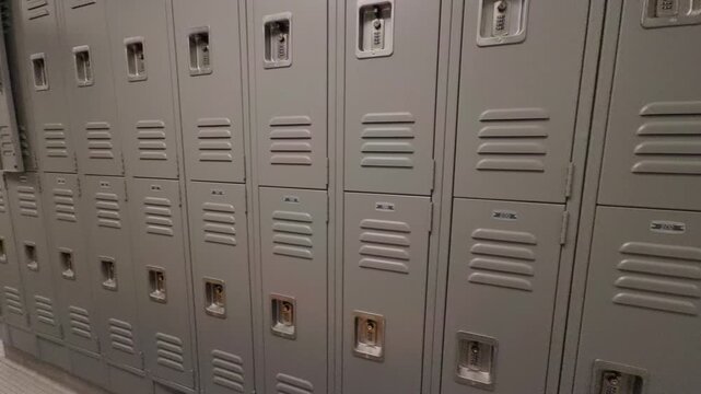 Wide angle slow motion pan revealing empty locker room with lockers and bench seating