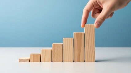 Hand placing final block on increasing wooden bar chart steps.