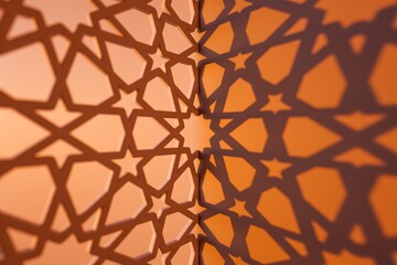 A close-up view of intricate star-shaped shadows cast on an orange wall, creating a beautiful geometric design.