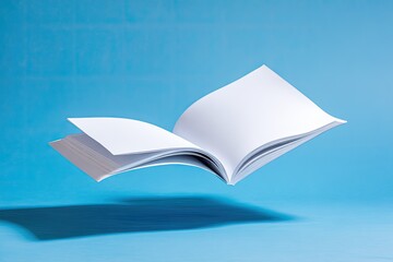 Floating open blank book with white pages on a light blue backdrop