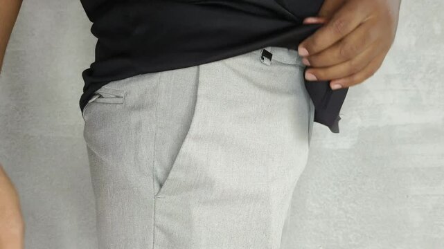 Hand of an Indian traveler placing Indian passport official citizenship identification document into a pant pocket. International travel and tourism concept. Closeup side view.