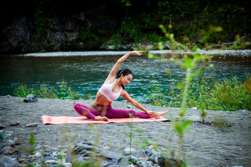 Young Japanese woman practicing side stretch yoga pose by a river, active outdoor wellness lifestyle with mindfulness, sustainability and mental wellbeing focus