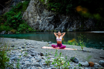 Japanese woman practicing gentle yoga stretching outdoors by a river
