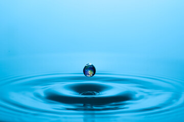 A single water droplet reflecting the globe creating environmental imagery