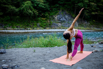 Woman Performing Standing Yoga Stretch with Side Bend Outdoors by Riverside