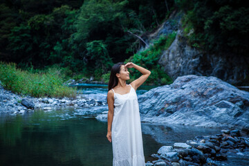 Fototapeta premium Thoughtful Woman Enjoying Quiet Moments by a Clear Mountain River