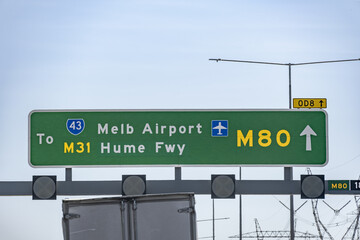 Overhead freeway direction sign indicates the route to Melbourne Airport and the M31 Hume Freeway via M80 Ring Road.  Road infrastructure, airport access and highway network in Australia