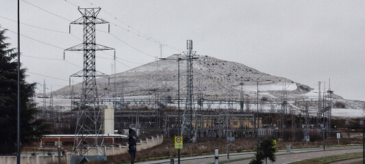 Paisaje urbano invernal con carretera asfaltada carril bici y colina nevada bajo un cielo nublado...