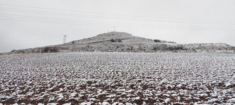 Paisaje rural de campo invernal con vegetaci&oacute;n cubierta de escarcha y colina nevada bajo cielo gris en Burgos, Espa&ntilde;a