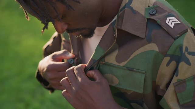 Soldier Ready Outside, Uniformed Personnel Prepares For Patrol In Morning Light Outside, An Armed Sergeant Adjusts Camouflage Attire Meticulously Before Starting Morning Patrol Outdoors