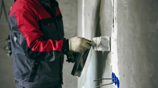 Professional Worker Meticulously Covering Electrical Socket With Plaster During Renovation Process