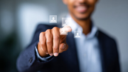 Businessman uses digital interface. A man touches a digital screen displaying user icons in a modern office setting during the day.