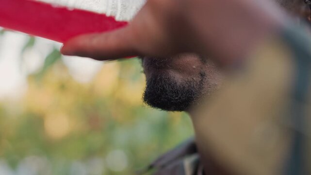 field medic accepting drink during patrol closeup, man in camouflage receives cup from unseen hand, small moment of relief and care captured with detailed profile, warm late light and quiet gratitude