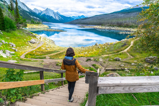 Hiker walking down wooden stairs to medicine lake in jasper national park
