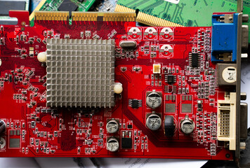 Red printed circuit board with heatsink and electronic components. Computer hardware and electronics technology background.