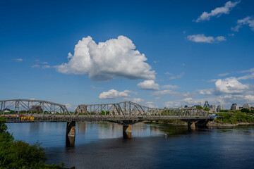 Obraz premium Steel truss bridge over river under blue sky with clouds