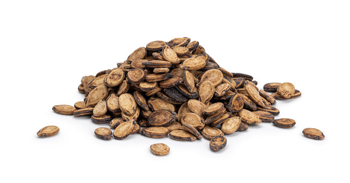 Dried watermelon seeds forming a big pyramide shaped pile on a solid white surface