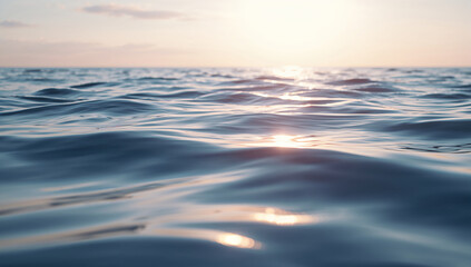 Serene deep blue ocean waves reflecting the soft golden light of the setting or rising sun at the horizon