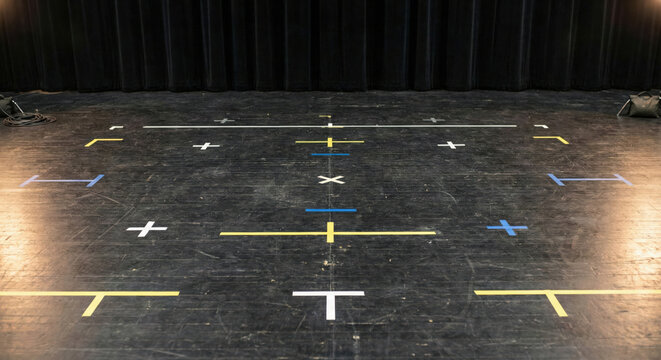 Marked stage floor with tape indicating positions for actors, creating a structured and organized performance space