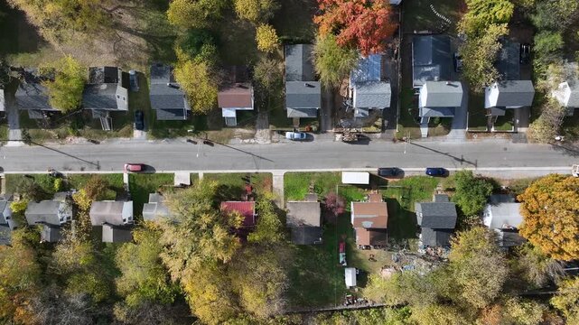 Charming american neighborhood with row of houses and colored trees. Sunny day in fall season. Aerial top down flyover. Peaceful suburb housing area in USA.