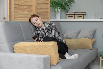 Young woman chilling or bored on couch with smartphone. Teen girl on sofa browsing social media or gaming. Relax, lifestyle concept for mobile app usage.