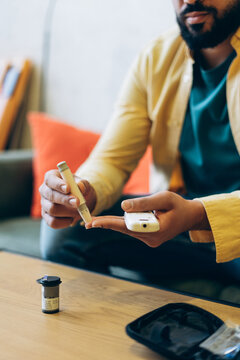 Man checking blood sugar using lancing device and glucometer selective focus closeup