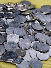 A scattered pile of silver Malaysian sen coins resting on a textured green fabric surface. © Reduan638