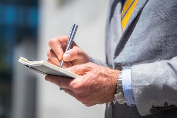Businessman writing notes in office notebook